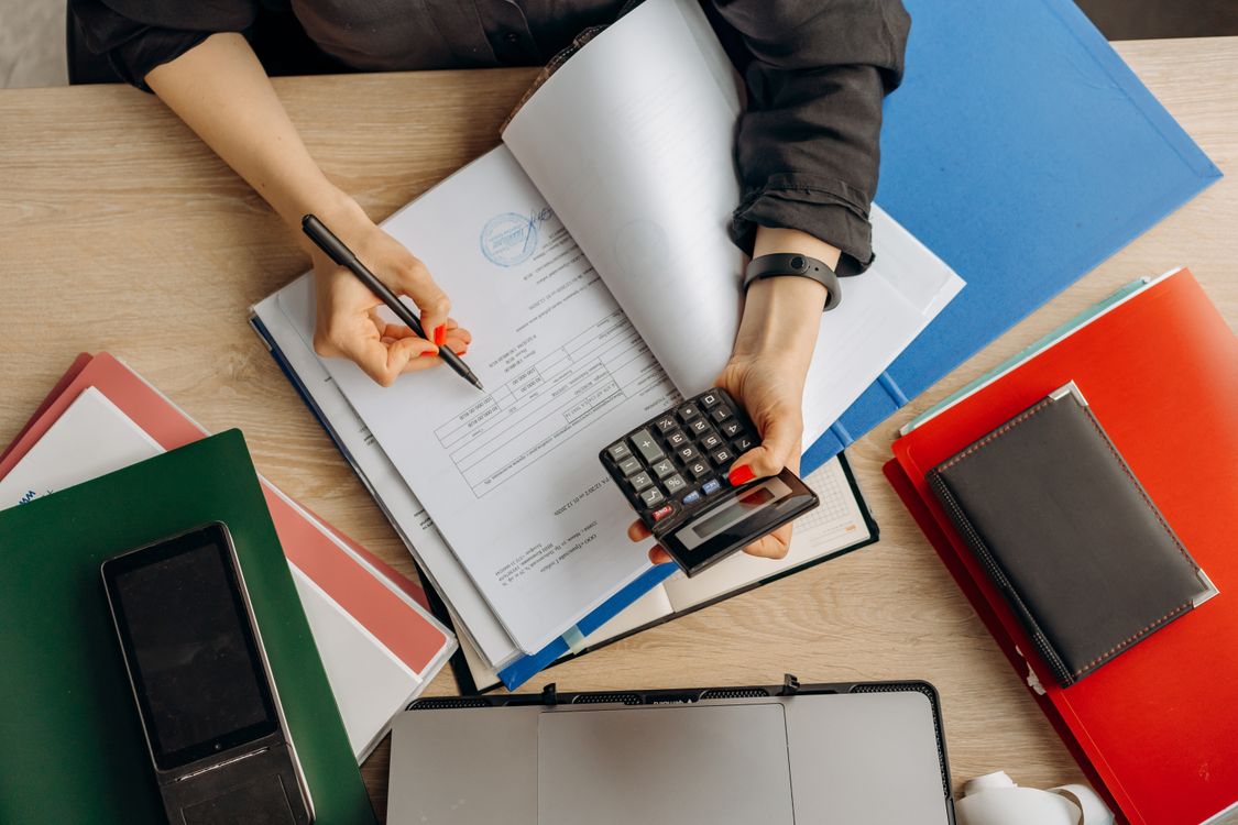 An accountant reviewing financial records with a calculator at a desk